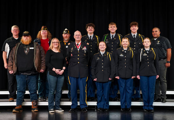 service members and student JROTC members pose onstage in a group