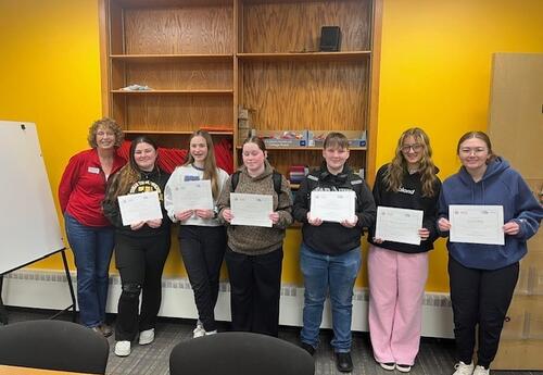 six students stand next to older woman, holding certificates