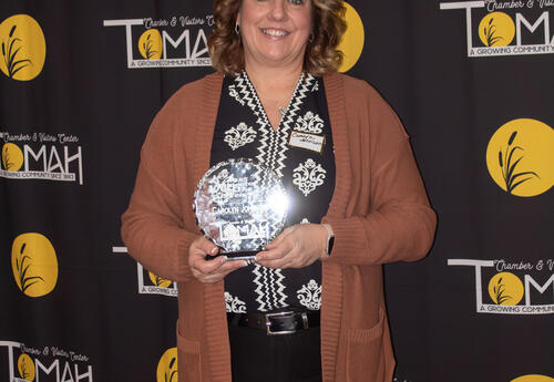 woman stands holding glass trophy
