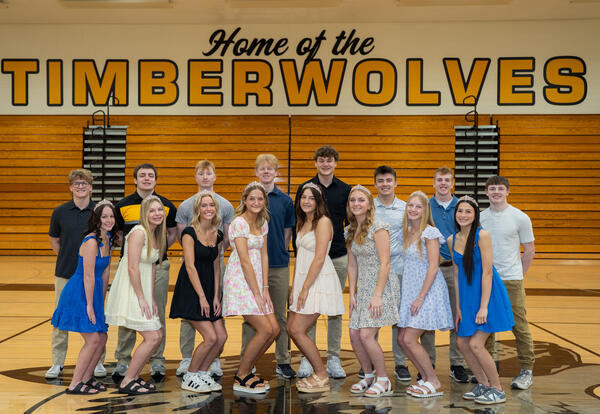 row of boys and row of girls posed in gymnasium, girls wearing crowns