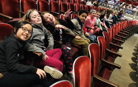 Students sitting in a row of theater chairs