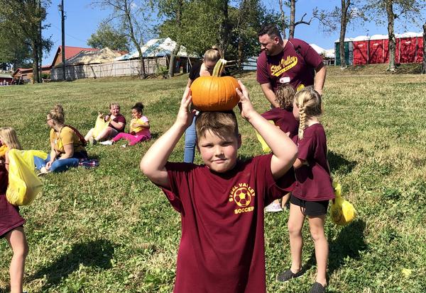 Child holding pumpkin over head