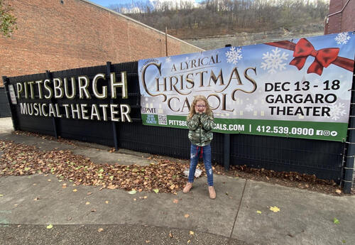 Student standing in front of an outside banner