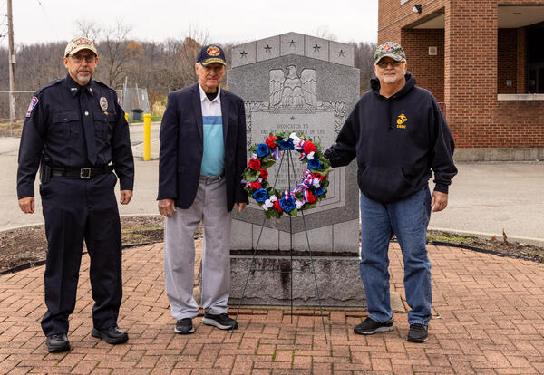 Three veterans with a wreath in front of a memorial