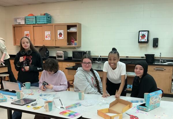 Five students at a table smiling and playing games