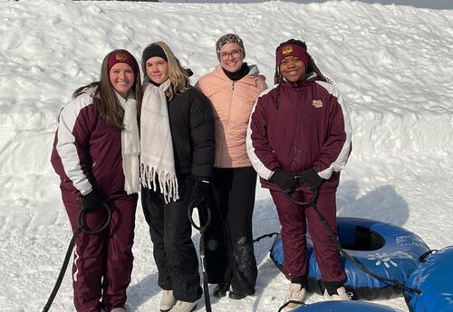 Four senior students pose together in the snow