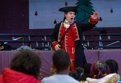 A man dressed as George Washington speaks with students.