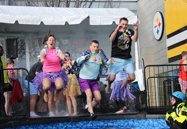 Three SV staff members jumping into a pool