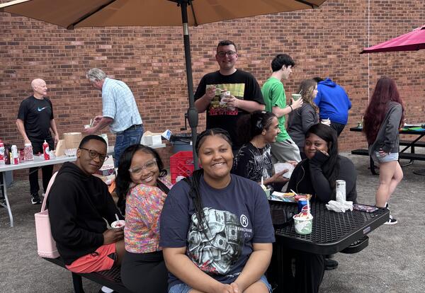 Smiling students gather around a picnic table
