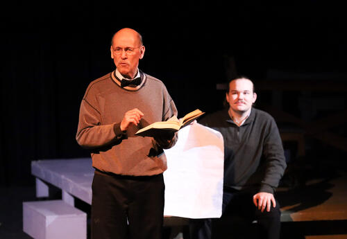 Performer on stage holding a book.