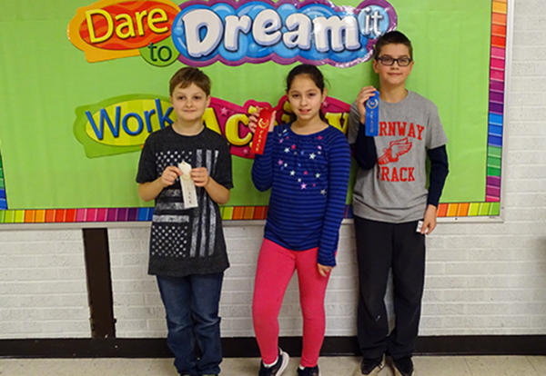 three spelling bee winners holding ribbons