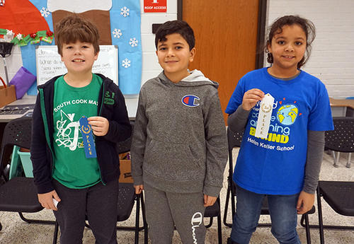 three spelling bee winners holding ribbons