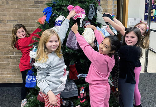 Students hanging clothes on a Christmas tree