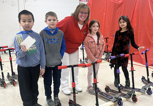 Smiling students with Fernway Principal with scooters