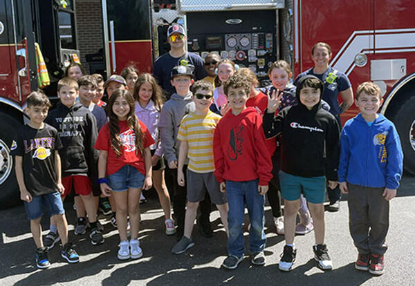 Third grade class pose with Tinley Park fire fighters in front of fire truck