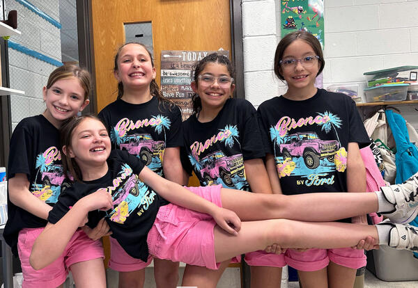 Four girls pose in brightly colored matching outfirts for matching day