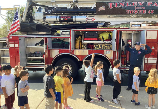 Student admire fire truck with firefighters during Fire Prevention Week