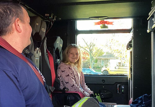 Students smiles in fire truck while getting a ride to school