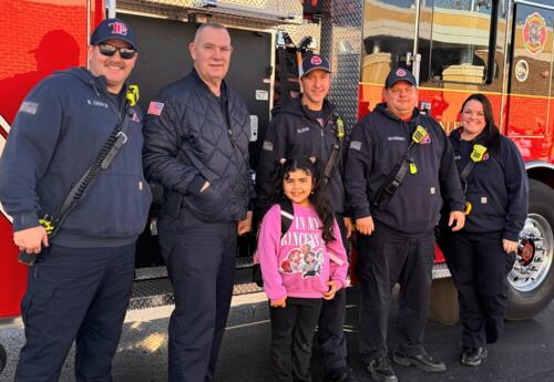 Fire prevention poster contest winner poses in front of fire truck with fire fighters