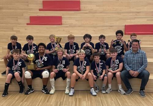 Grissom 6-7 grade boys' volleyball team pose proudly with coach after winning tournament championship