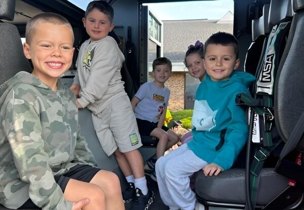 Five students smiling while sitting in fire engine