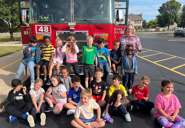 Ground of students pose in from of fire truck for group picture