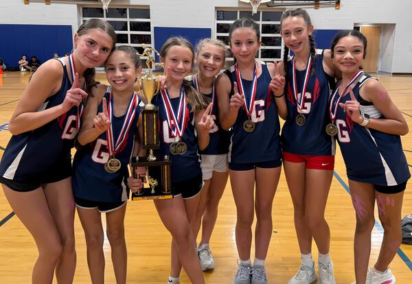 Grissom girls' cross country team pose proudly with first place trophy and medals at conference meet