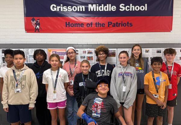 Twelve Grissom Students of the Month pose proudly in front of lockers and school banner