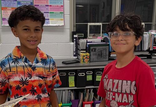 Two students smile while holding their projects they worked on at family reading night