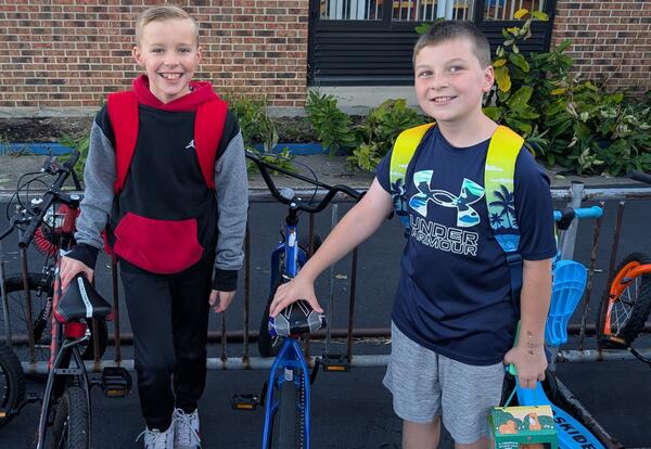 Two McAuliffe students smile in front of their bikes outside of school on Walk and Roll to School Day
