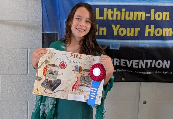 Grand prize Tinley Park Fire Prevention poster contest winner poses proudly with her poster and ribbon at awards breakfast
