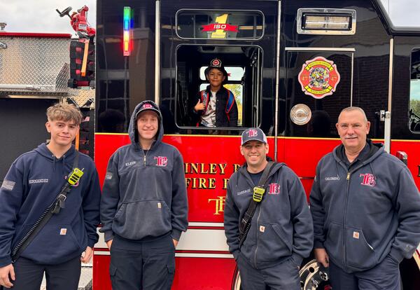 First grader fire prevention poster contest winner poses proudly in fire truck and fire fighters when he arrives at school