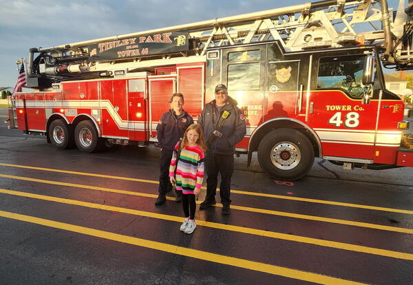Third-grade fire prevention poster contest winner poses with Tinley Park fire fighters after receiving a ride to school in a fire truck