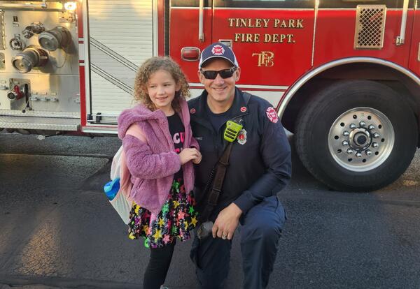 Second grade fire prevention poster winners poses with Tinley Park fire fighter after getting a ride to school in a fire truck