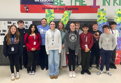 Grissom December Students of the Month pose proudly in hallway in front of lockers and Patrtiot banner