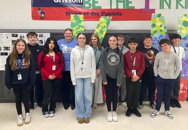 Grissom December Students of the Month pose proudly in hallway in front of lockers and Patrtiot banner