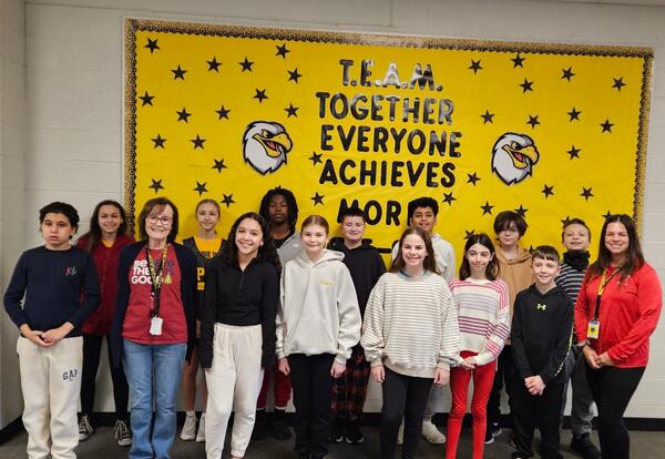 Prairie View December Students and Staff of the Month pose proudly in hallway in front on school bulletin board