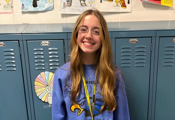 Prairie View Student proudly smiles in front of lockers for being recognized as the Patriot Pen Essay Contest winner