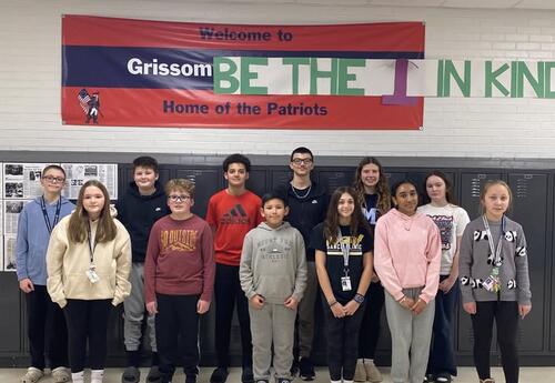 Grissom January Students of the Month pose proudly in hallway in front of lockers and Patrtiot banner