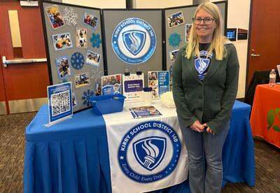 EC Program Coordinator poses is front of KSD 140 table display at Preschool Fair at the public library.