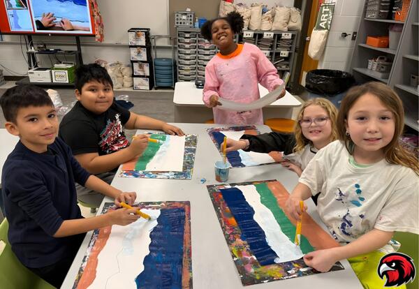 5 Children  smile while painting colorful abstract designs on large paper sheets at a classroom table filled with art supplies.
