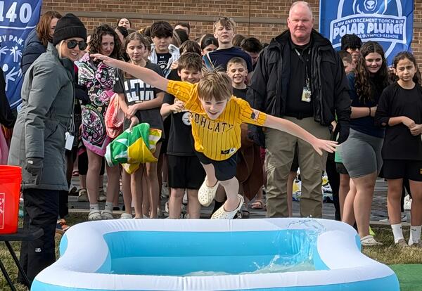 Student diving into pool during Polar Plunge event.