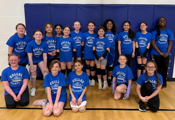 Girls Volleyball Team poses for team picture in  gym wearing matching blue shirts
