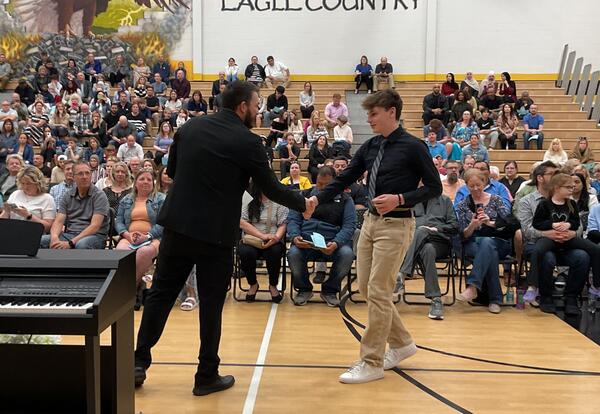 Vice principal shaking student's hand during NJHS Induction Ceremony in school gym