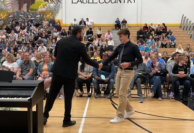 Vice principal shaking student's hand during NJHS Induction Ceremony in school gym
