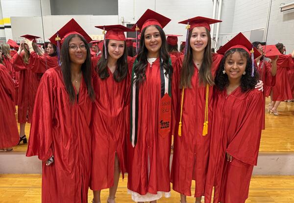 Group of students pose proudly in caps and gowns before graduation ceremony