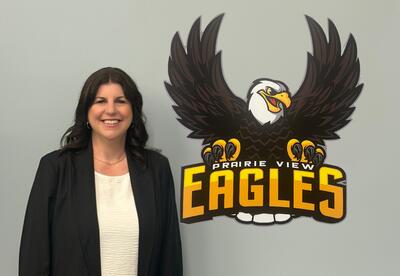 Newly appointed assistant principal stand next to Prairie View eagle logo in boardroom