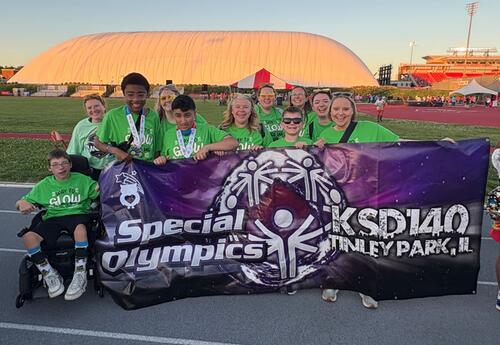 Student and staff holding KSD 140 Special Olympics banner at summer games