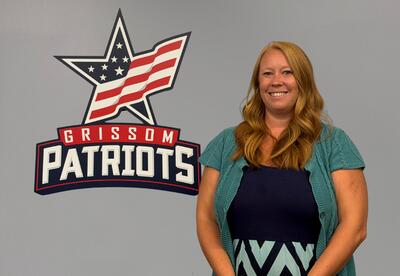 New Grissom Assistant Principal stands to the right of Grissom star logo hanging on wall