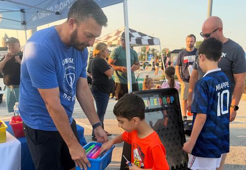 Student picking out prize in bucket held by principal at National Night Out